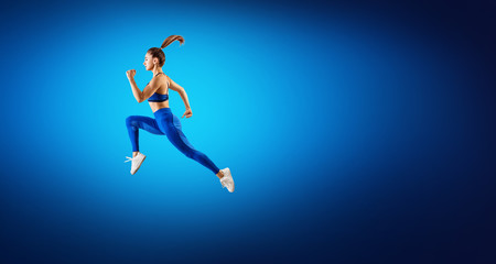 Young woman runner in blue sportwear jump in the air.
