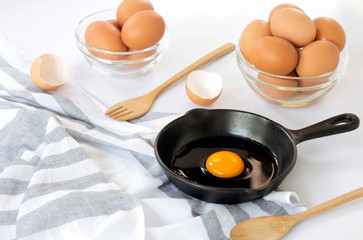 Raw eggs in a pan and egg bowl on a white background