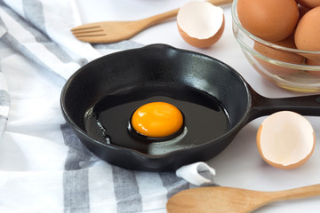 Raw eggs in a pan and egg bowl on a white background