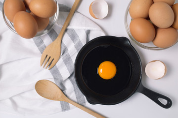 Raw eggs in a pan and egg bowl on a white background