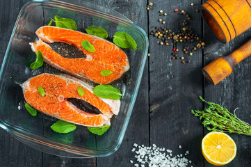 Two steaks raw trout glass tray with lemon herbs and spices. Top view.