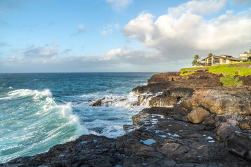 Ocean surf hitting the basalt cliff as water from previous wave back flashing to the sea, Kauai,...