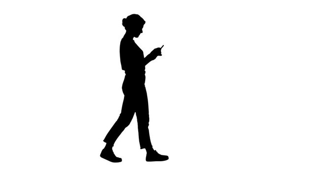 Silhouette Beautiful young woman walking and reading text message on her mobile phone.