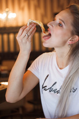 Hipster girl eating pizza in the restaurant and enjoying this