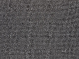Fototapeta na wymiar Texture detail of a dark gray acrylic polyester material blend is shown in a closeup view.
