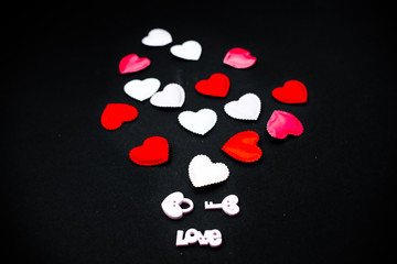 Love heart fabrick hearts. Confetti hearts on black abstract background top view horizontal several objects.