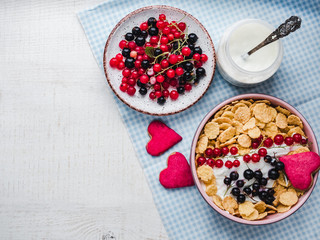 Festive and healthy breakfast for loved ones. Cereal biscuits in pink glaze, vintage bowls, cornflakes, granola, yogurt, fresh berries. Close-up, top view. Concept of healthy and delicious food
