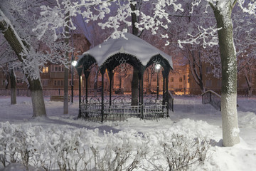 snow-covered gazebo in the city Park on a winter night