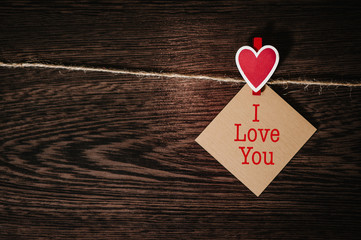 Text I love you. Craft paper, one blank, with red heart hanging on lacing or rope on background with space. Place for text. concept of St. Valentine's Day. International Women's Day, eighth of March.