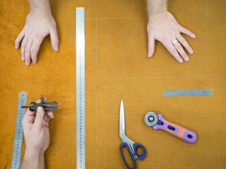 Hands of the master and studend. Marking leather for making bags, purses or shoes.