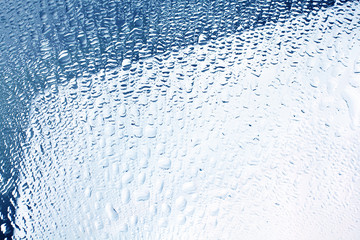 Many small drops of water glass surface, window in the raindrops, mirror in the drops of condensate water in bright blue color, abstract design background, wet textured gradient pattern, close up
