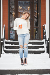 Beautiful natural young smiling shy friendly blonde woman wearing knitted sweater and plaid on a grey background.