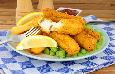 Fish fingers and chips meal with mushy peas on a wooden background
