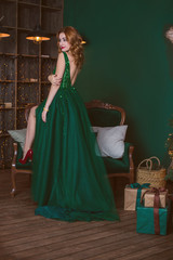 Fototapeta na wymiar Winter holidays, celebration and people concept - young sexy woman in elegant green evening dress over christmas interior background