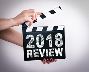 2018 review concept. Female hands holding movie clapper