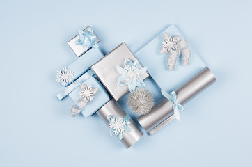 Christmas background -  heart shape of soft pastel blue and silver gift boxes with bows on blue backdrop, top view. Winter love backdrop.