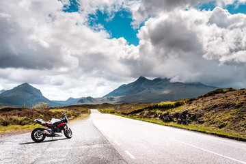 lonely road on the isle of skye, with a motor bike in a empty landscape scenery in scottland great britain, typical skye weather on a moody summer day with some rain in the morning