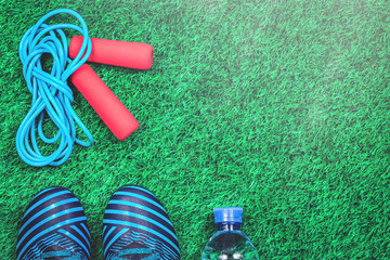 Skipping rope, water bottle and cleats against green artificial turf