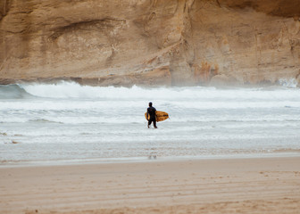 surfer walking on beach