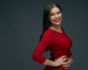 smiling woman in red dress holds hands on his hips.