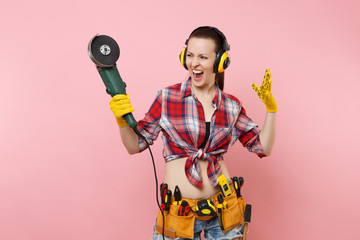 Strong energy handyman woman in yellow gloves, noise insulated headphones, kit tools belt full of...