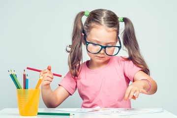 beautiful cute little girl drawing picture on white paper with colorful pencils