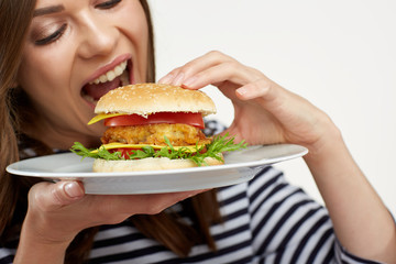 portrait of woman eating burger on white plate.