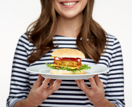 woman holding burger on white plate.