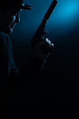 Portrait of side of man in black hat with pistol