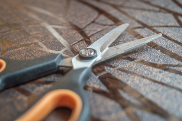 black and orange coloured scissors kept on a textured brown table