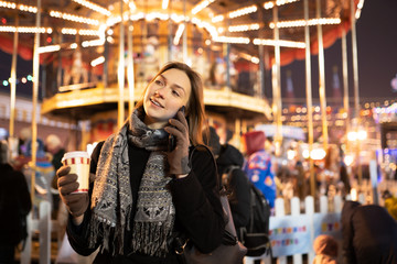 Picture of happy woman with glass and phone in hands in evening for walk