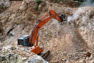 Large hydraulic Jackhammer working on smashing rock.