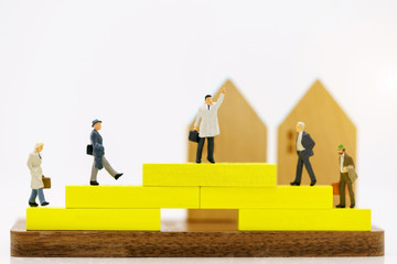 Miniature people: Businessmen standing on yellow block with houses.  Concept of the path to purpose and success,  Financial and money.