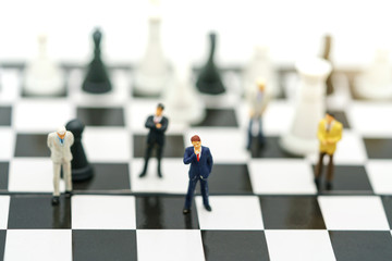 Obraz premium Miniature people: Businessman handshake to business success on chessboard. Commitment, agreement, investment and partnership concept