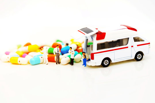 Miniature people: Doctor and patient standing with ambulance  and drugs. Health care and emergency concept.