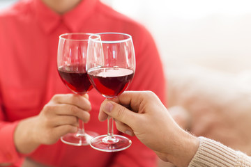 celebration, drinks and alcohol concept - hands of couple clinking red wine glasses