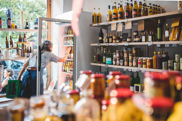 Female employee arranging bottles in refrigerator at deli