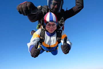 Tandem skydiving. Girl-passenger is having fun in the sky.