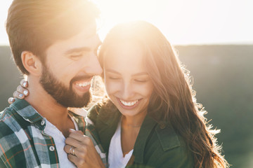Young beautiful couple walking outside on beautiful sunset. Perfect romantic landscape for lovestory. Two hipsters-lovers hugging.