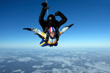 Fototapeta na wymiar Tandem skydiving. Girl-passenger is having fun in the sky.