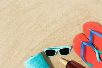 vacation, travel and summer holidays concept - straw hat, flip flops, sunglasses and sunscreen oil with seashells on beach sand