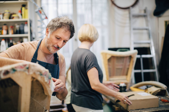 Male upholsterer stitching sofa in workshop