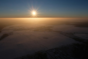 The sun is above snowy land.
