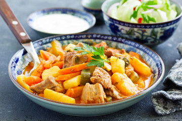 Beef stew with tomato sauce in a pan on wooden background. azu.