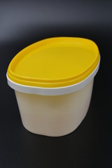White plastic container for food and mayonnaise with a yellow cap on a black stylish background