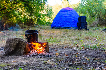 Cooking food in a kettle on bonfire. Tent on background