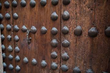 A locked wooden door with iron nails on it. The door seems to be closed and looks very protective and strong.