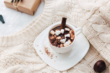 Hot cocoa with marshmallow on knitted sweater. Cozy holiday concept