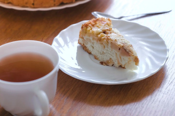 Slice of homemade apple pie and hot tea on the table.