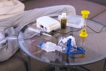 Preparation for inhalation at home. Nebulizer, mask and medicine on the glass table.